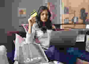 Woman laying on couch with credit card in her hand