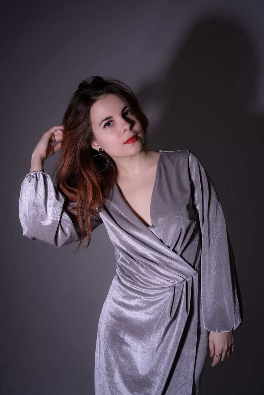 Woman standing wearing a gray long sleeve wrap dress