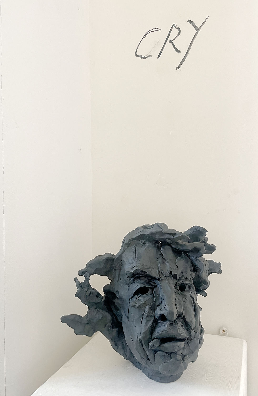 A Stoneware Ceramic and Graphite sculpture of a male head with the word 'cry' written above