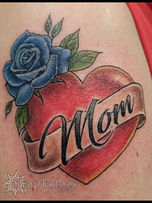 Tattoo of a blue rose with a heart and a banner that says mom