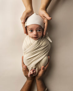 Tiny baby hand wrapped around parent's hands