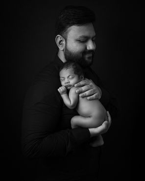 Artistic composition of newborn lying on father’s chest