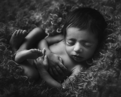 Fine art newborn image with deep shadows and moody tones
