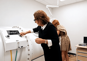Anti Aging Associates clinical room with a specialist adjusting a white hyperbaric chamber