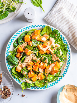 Frisk salat med spinat og søtpotet servert på et fat