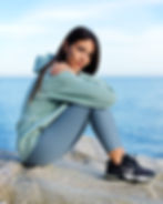 Woman sitting on a cliff by the sea in workout clothes.