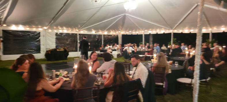 Wedding reception guests dine under a tent