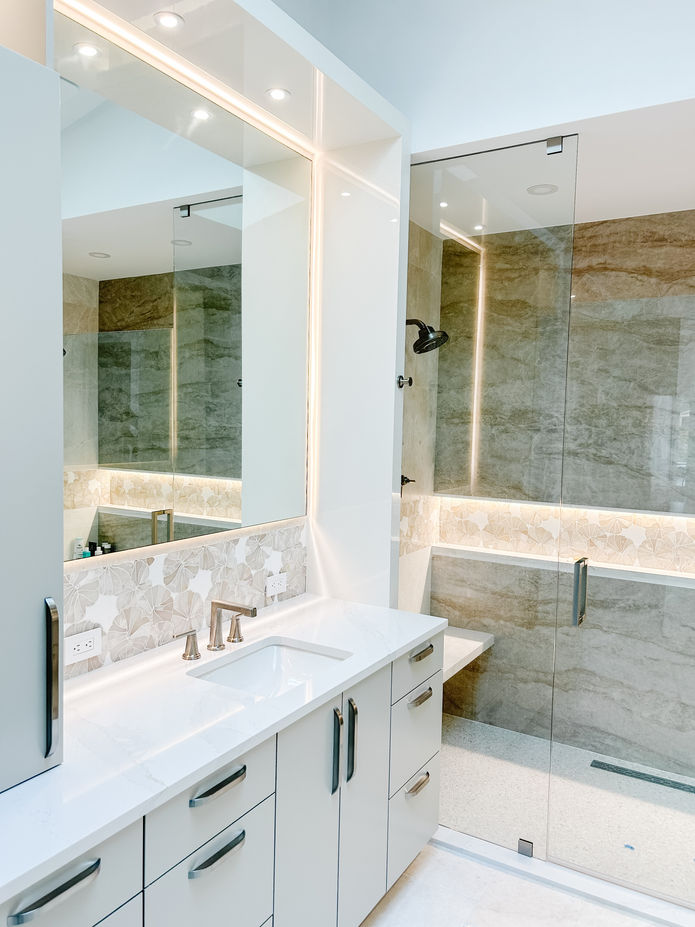 Modern bathroom with a white vanity and large mirror design with inset lighting.