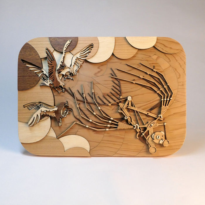 Obra de Arte realizada con Madera Natural Maciza cortada con Laser Cut, sin tintes, solo Cera Natural. Ilustración Volumétrica en Relieve de Tomàs Bases. Vemos un Pequeño Osito de Peluche volando con una Máquina Voladora de Leonardo Da Vinci. Unas Gaviotas la Atacan en pleno vuelo. Merece especial atención la complejidad del Diseño de las Alas de las Gaviotas. En conjunto, es un compendio de Ilustración, Artesanía y Escultura con una temática Fantasiosa original de Tomàs Bases.