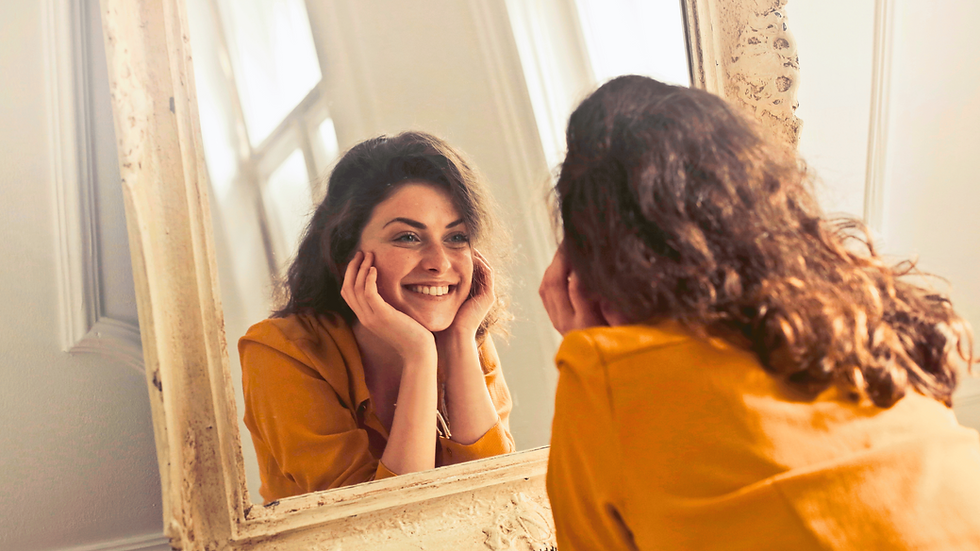 Eine Frau guckt liebevoll in den Spiegel