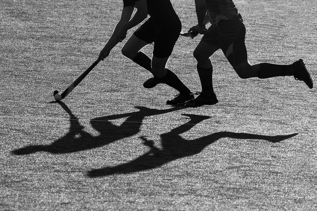 Silhouette. The shadow of a hockey players is running with a hockey stick on a hockey fiel