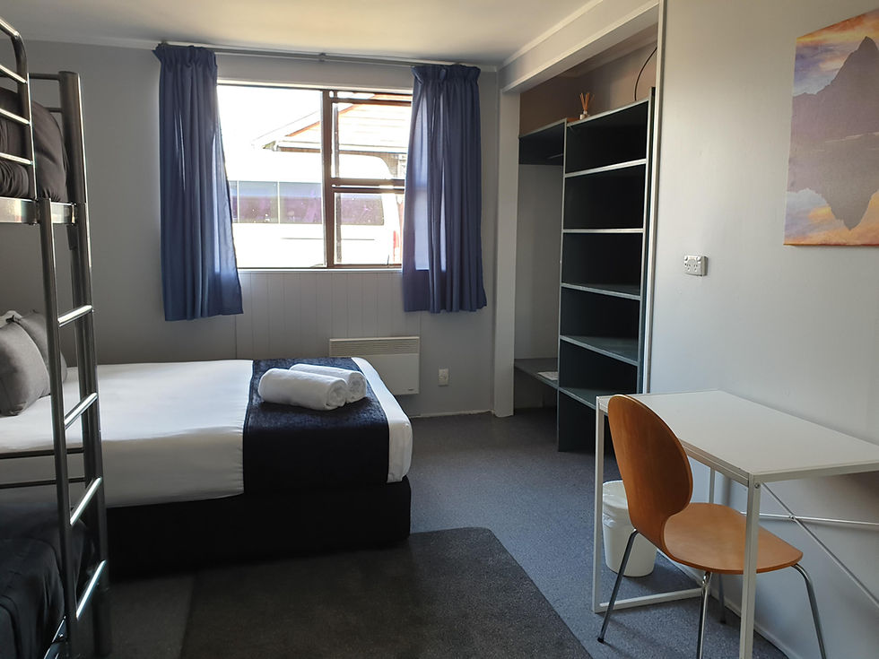 A double bed with a bunk bed and desk adjacent.