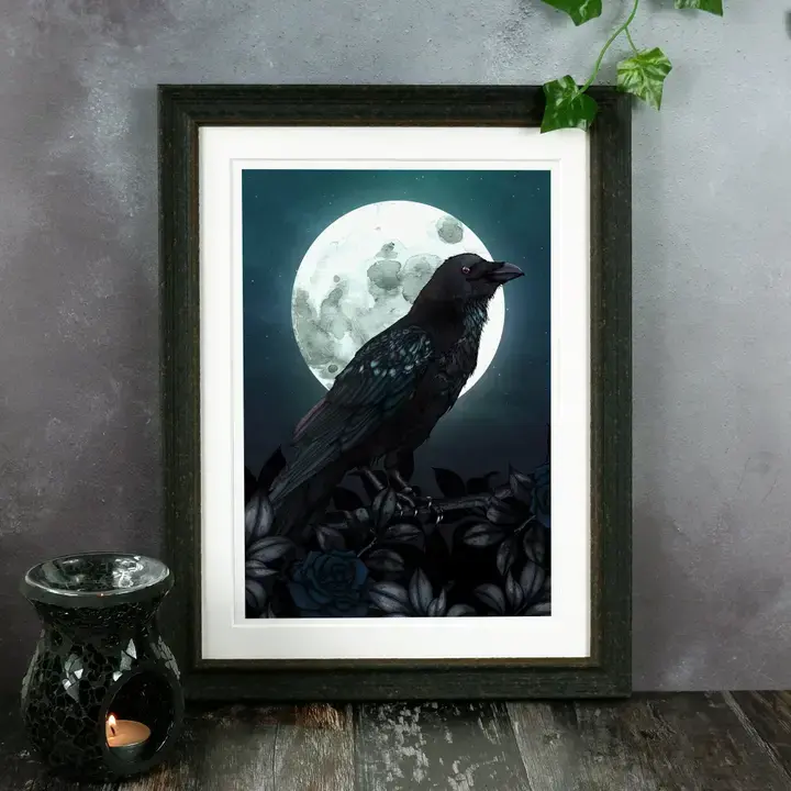 Une illustration dans un cadre représentant un corbeau magnifiquement détaillé sur une pleine lune, entouré de roses sombres.