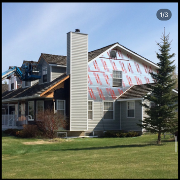 A two-story home with a completed asphalt shingle roof and brick chimney.