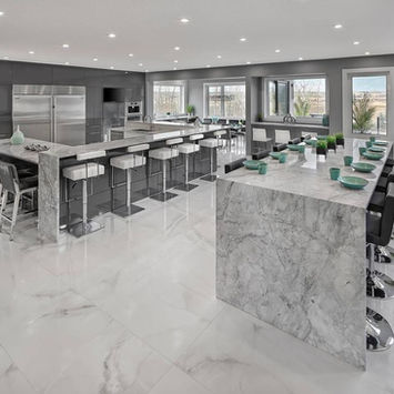 Modern kitchen with a large marble island, barstools, and stainless steel appliances.