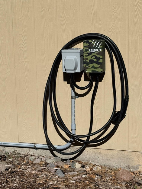 Grizzl-E EV charging station installed on exterior wall with coiled cable Montrose Colorado by Crosstech Electric