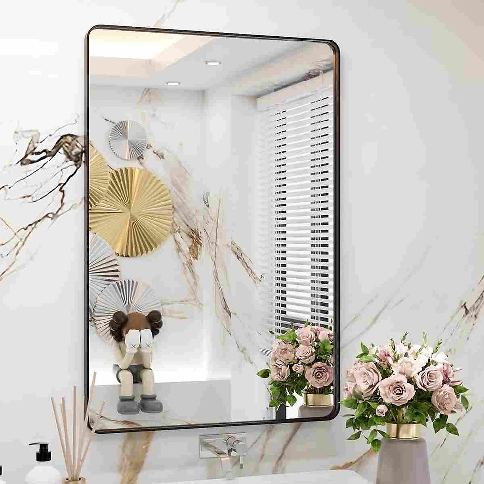 Mirror reflecting abstract art and a seated figurine in a white marble room. Nearby, a vase of pink roses adds a touch of color.