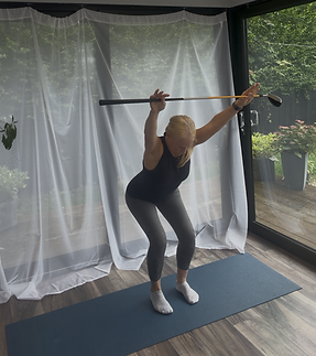 Woman performing a standing ilates stretch exercise with a golf club to improve mobility and golf performane