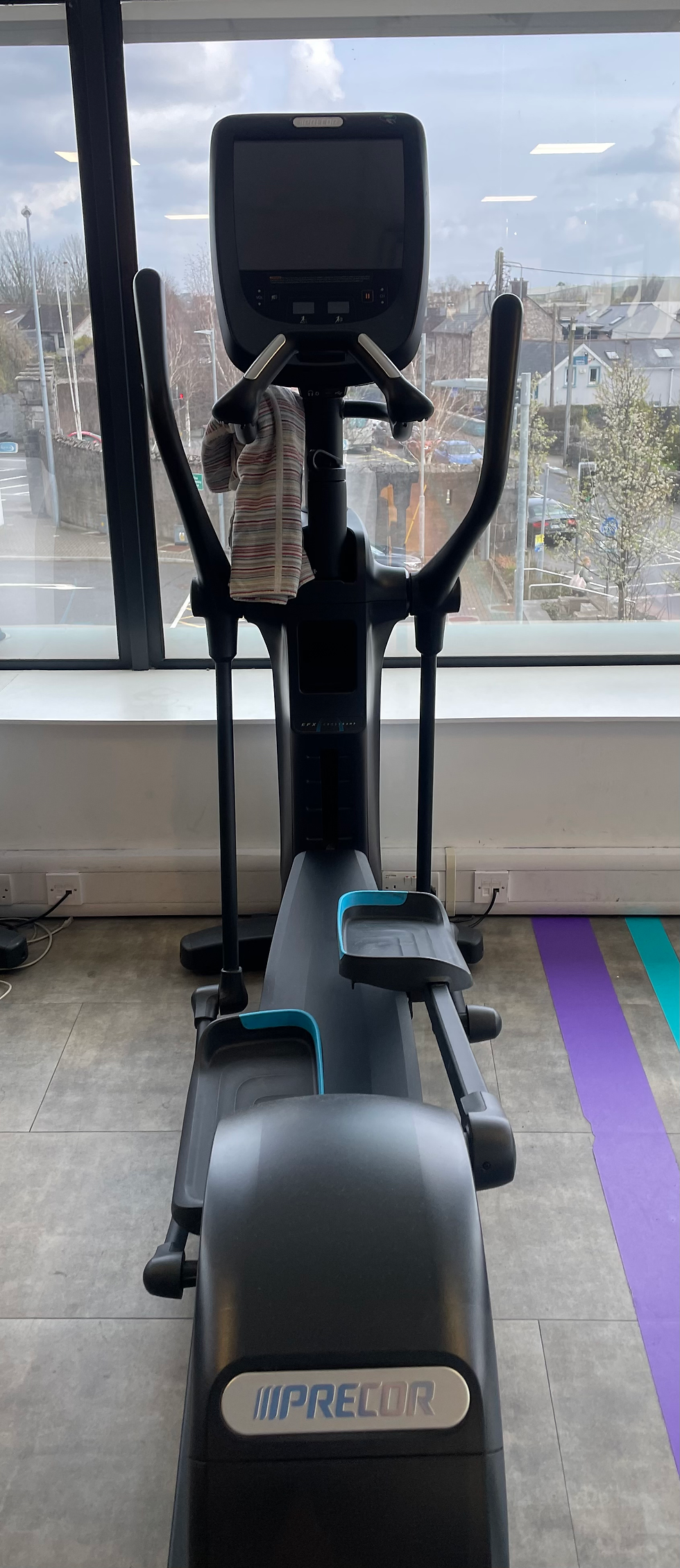 Cross trainer in a gym facing out a window.