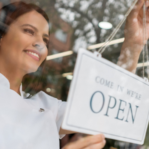 esthetician with open sign at her spa business