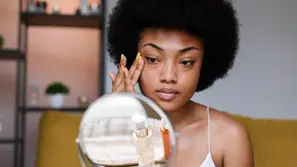 a woman evaluating her skin looking in a mirror.