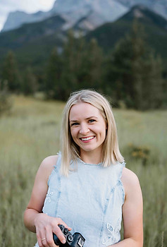 Naty holding her camera furing a family photo session in Canmore at Quarry Lake Park