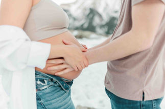 Dad to be placing his hands on the baby bump during a photo session