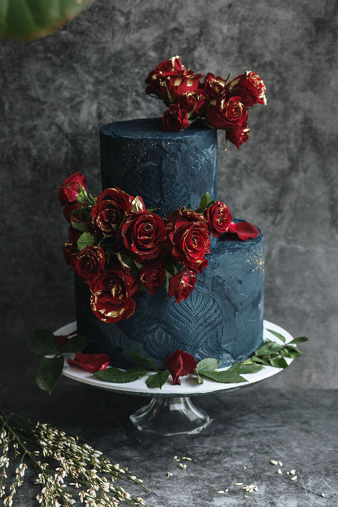 Dark and moody food photography of a textured blue celebration cake covered in Roses, by Beth Steddon, a photographer in Brighton