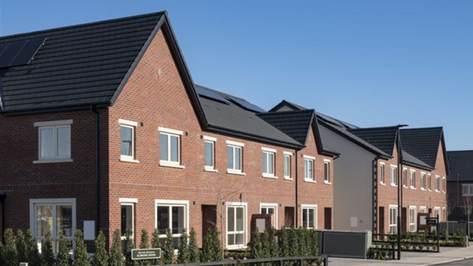 Cairn, Complete Mechanical and Electrical Fit-Out by Greenlight, Residential Development – Modern two-storey semi-detached homes with red brick and cream render facades, large windows, grey tiled roofs, and landscaped front gardens with young trees and hedges.