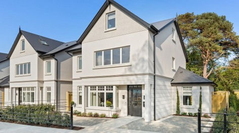 Durkan, Full Electrical Fit-Out by Greenlight, Residential Development – Elegant three-storey semi-detached homes with cream rendered facades, large windows, pitched dark tiled roofs, and landscaped front gardens, set in a leafy suburban setting.