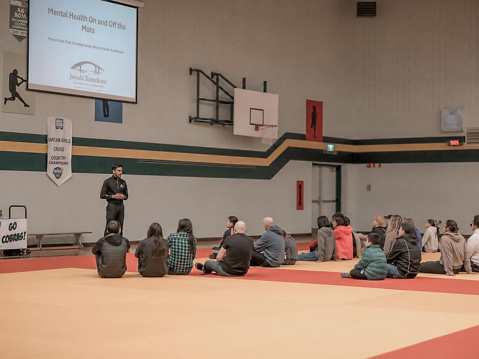 Jayoda Tennekone facilitating a group therapy session with participants seated in a gymnasium on Prince Edward Island