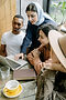 Diverse group of three professionals collaborating around a laptop in a café setting, representing SANGAT Consulting Collective's interdisciplinary and equity-centred approach to community work in Calgary