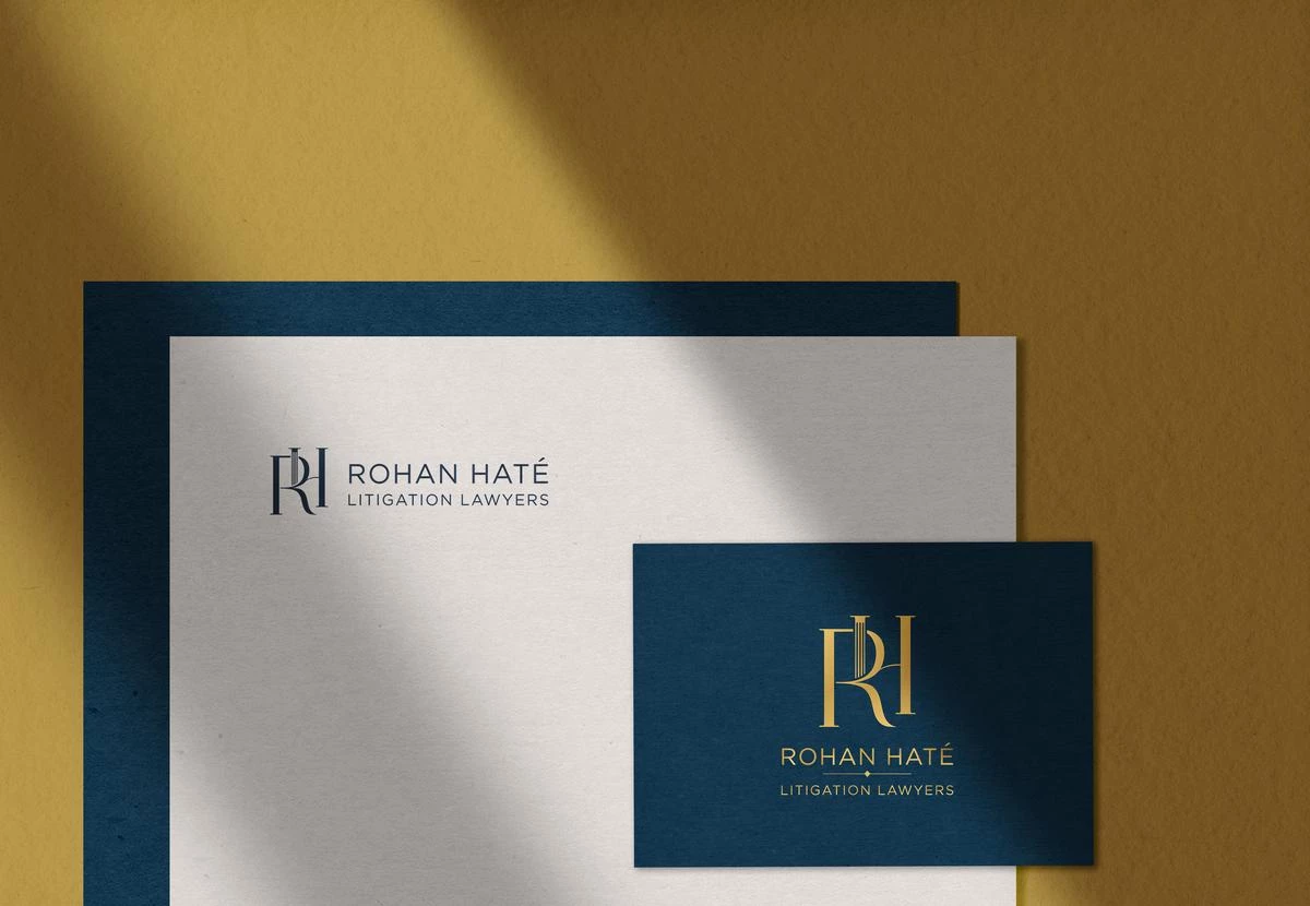 Image of Rohan Haté Litigation Lawyer logo design created and designed by Design Hour. the image shows the symbol in the foreground on a blue business card and the complete logo with the symbol and wordmark are shown on white paper in the background