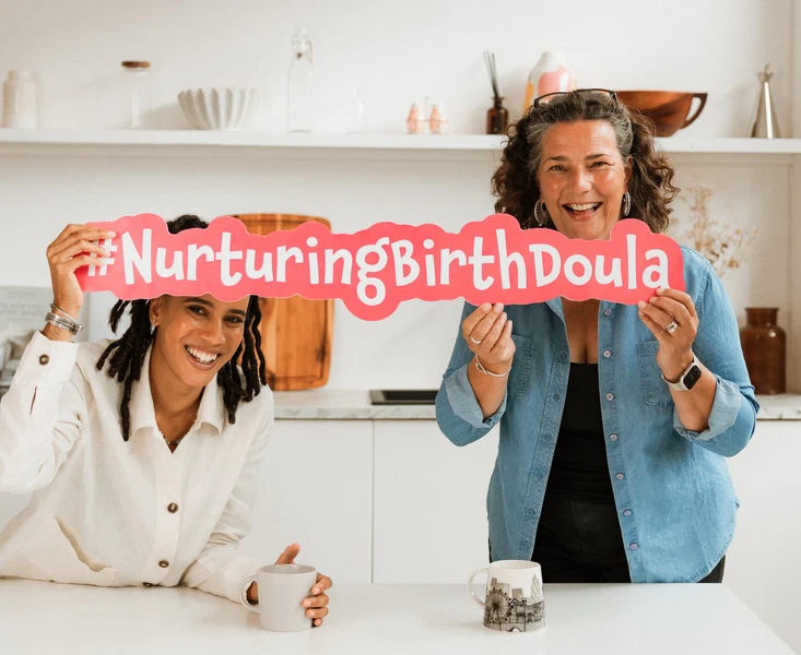 Sarah Sayer holding a #NurturingBirthDoula sign in a relaxed environment 