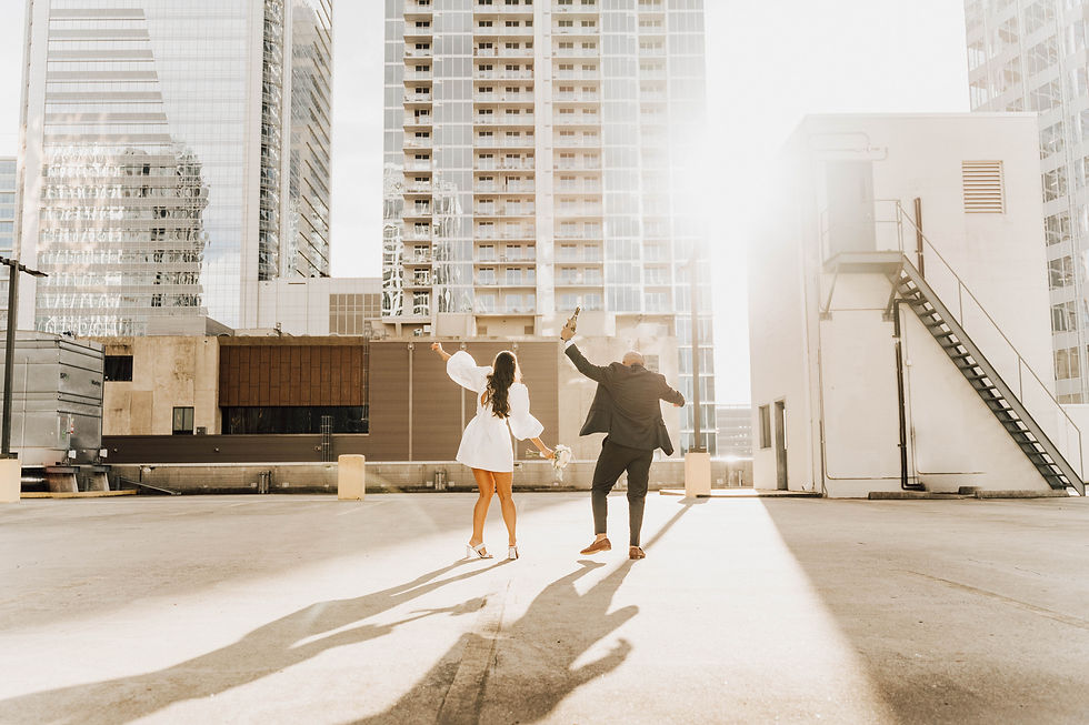 bride and groom dance on rooftop with champagne during Uptown Charlotte elopement