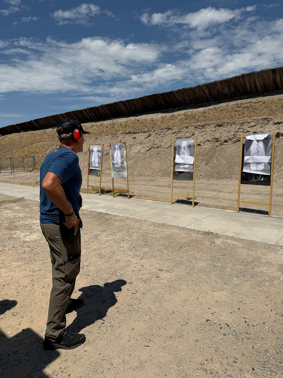 Man standing at outdoor shooting range with paper targets