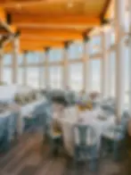 Palisades Hight Camp Elegant dining room with round tables, gray chairs, colorful floral arrangements, and large windows. Warm wooden ceiling and bright ambiance.