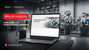 Laptop on desk in automated factory with robotic arms; text reads Why AI visibility now matters to manufacturing companies.