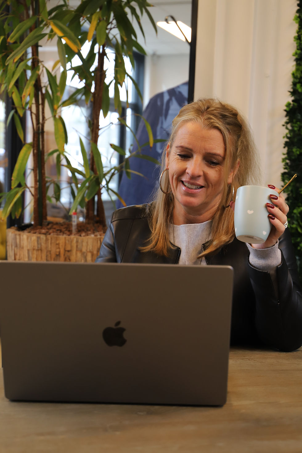 vrouw achter laptop met mok in hand