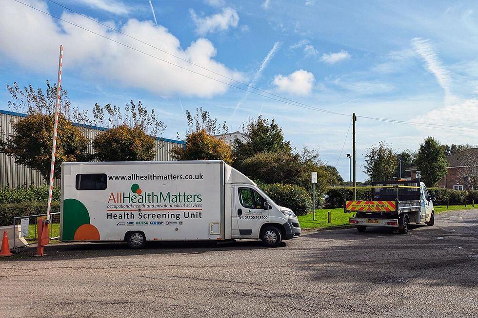 White AllHealth Matters Health Screening Unit van and highway maintenance truck parked roadside under a bright blue sky.