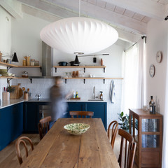 Rustic kitchen with wooden table, blue cabinets, and white lamp