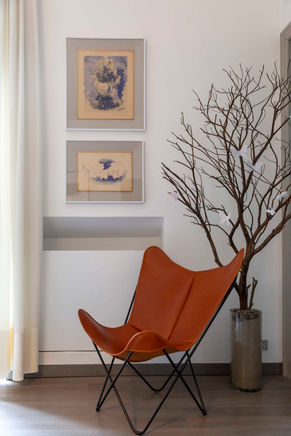 Brown leather butterfly chair, artwork, and branch decor