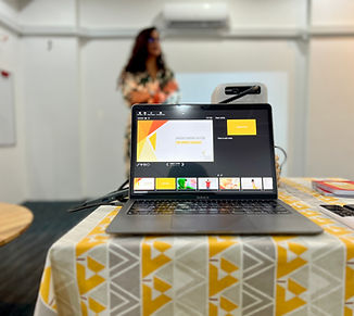 A laptop displaying a presentation slide on a table, representing professional teacher training, parent workshops, and speech-language therapy resources at Smilestones Cambodia center.