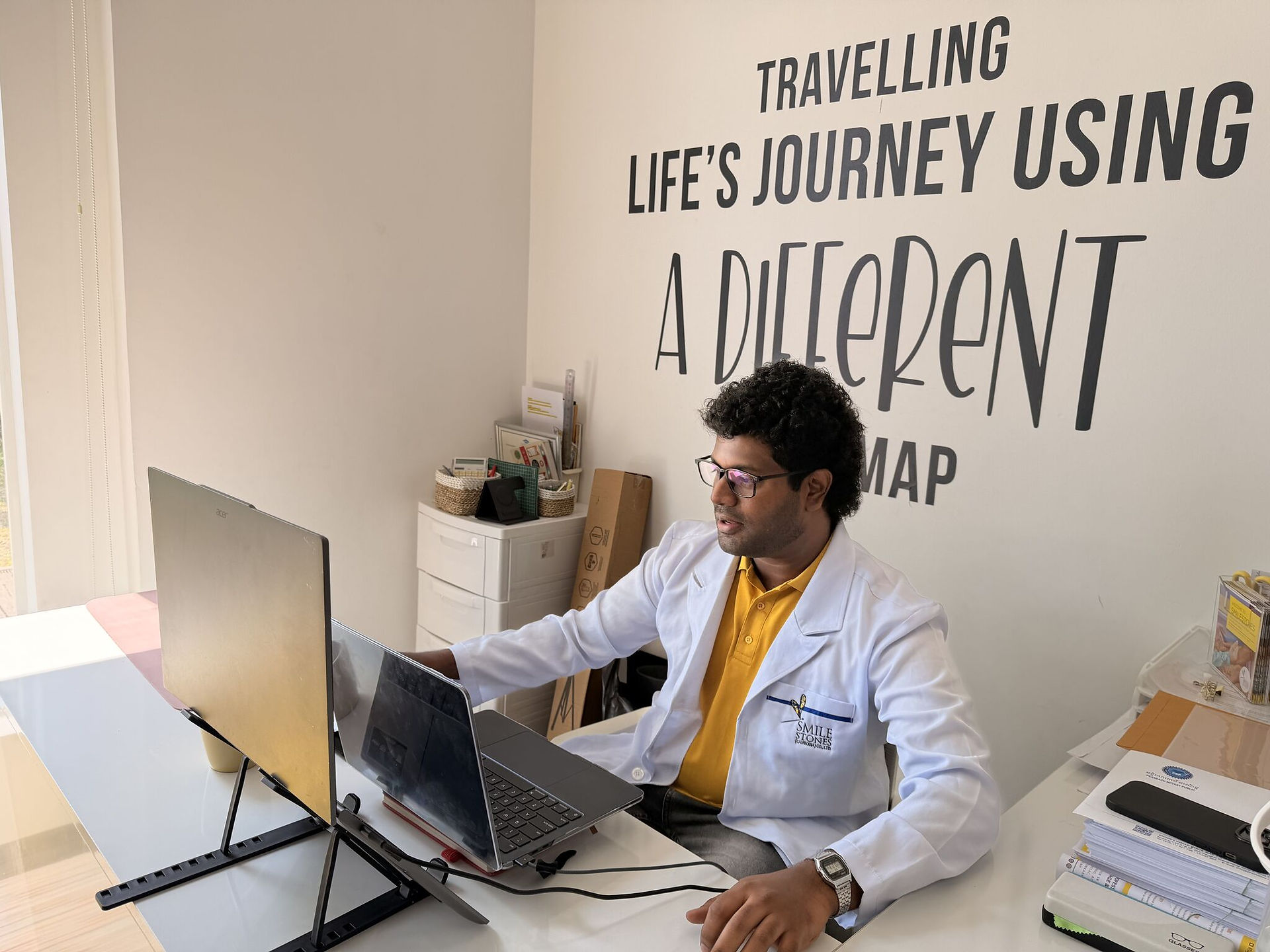 Smilestones Cambodia male speech-language pathologist working at a laptop in the office.