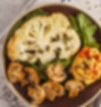 Roasted vegetables including cauliflower,  mushrooms on a bed of spinach in a bowl. 