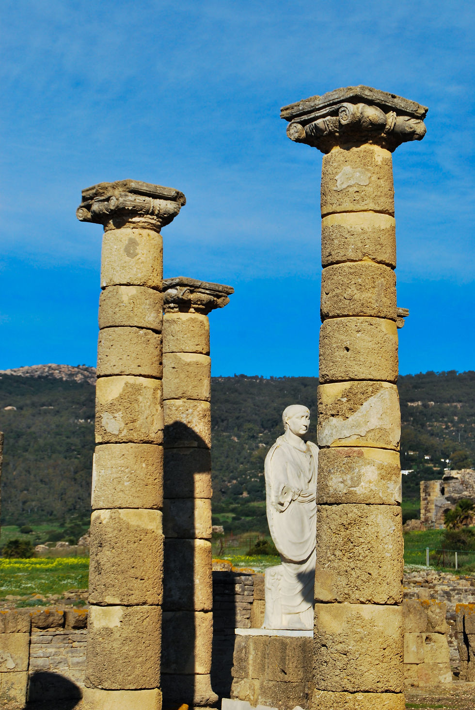 Tres conlumnas y una estatua de origen romano, al fondo se ve una montaña