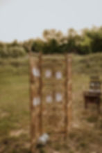 A bride and groom sitting on a couch in a field.