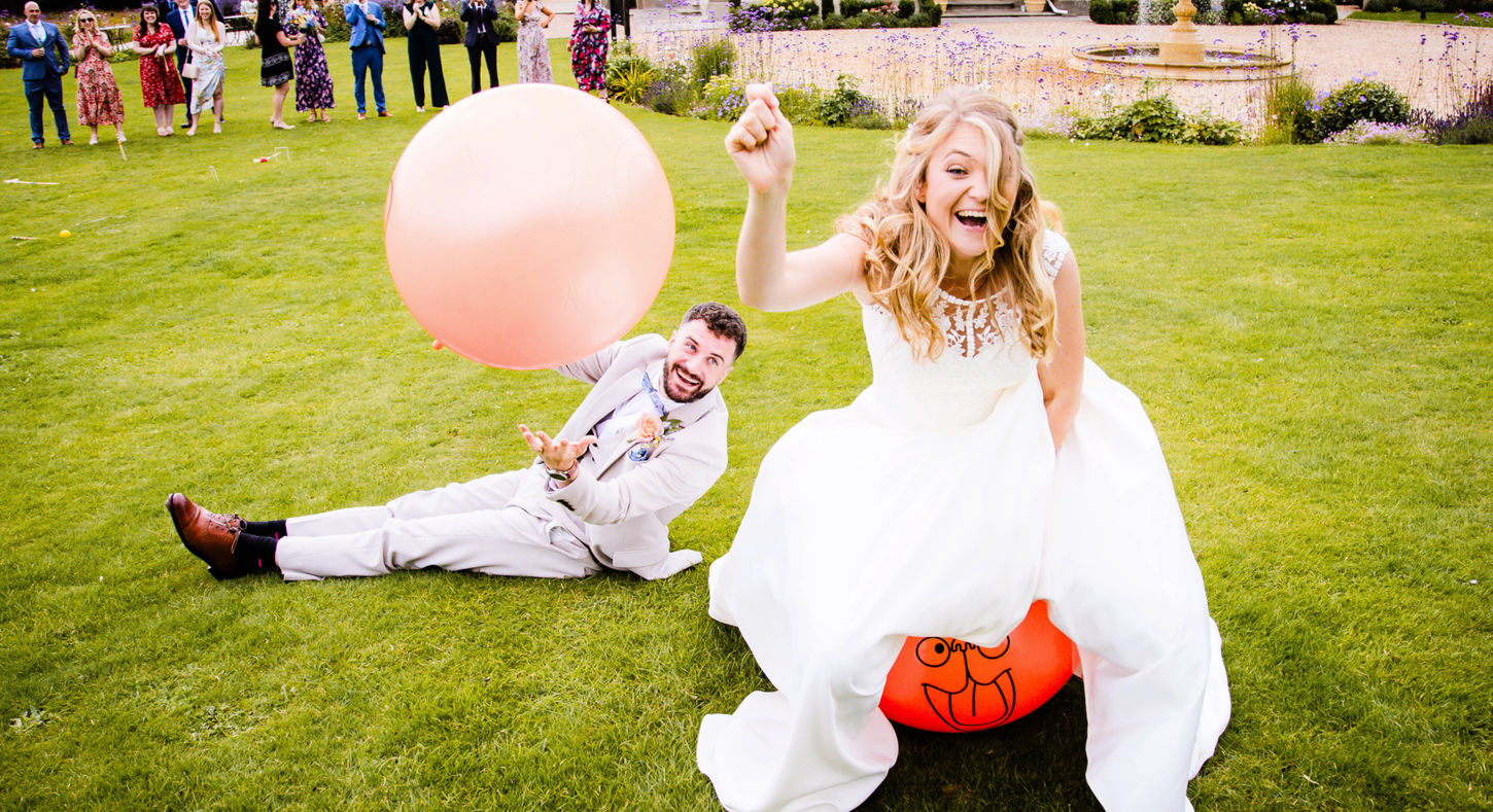 Fun photo of bride and groom on space hoppers at St Tewdrics House