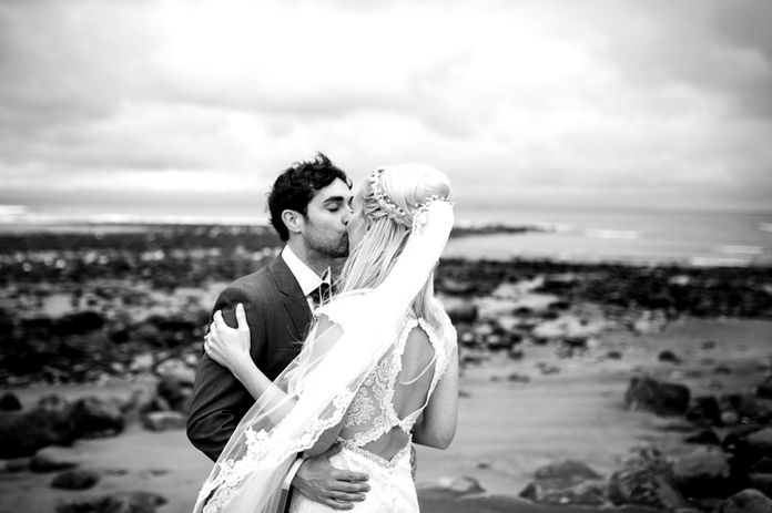 bride and groom kiss at coastal beach