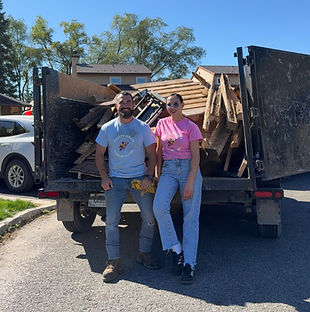 Two Mighty Mouse Junk Removal team members standing in front of their truck loaded with clean wood debris on a sunny day in Ottawa, after completing a deck teardown and cleanup job.